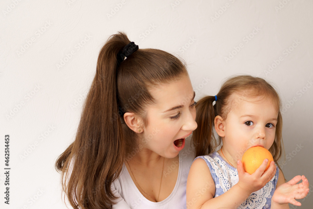 happy cheerful funny kids children with mom eat bite fresh fruits and vegetables at home. family eats lunch oranges, citrus apples bananas. Healthy eating, vitamins, diet, vegetarianism menu concepts happy cheerful funny kids children with mom eat bite fresh fruits and vegetables at home. family eats lunch oranges, citrus apples bananas. Healthy eating, vitamins, diet, vegetarianism menu concepts