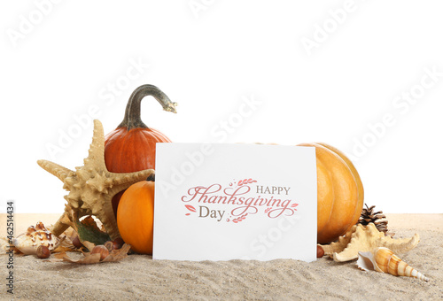 Pumpkins, starfish, seashells and card with text HAPPY THANKSGIVING DAY on sand against white background