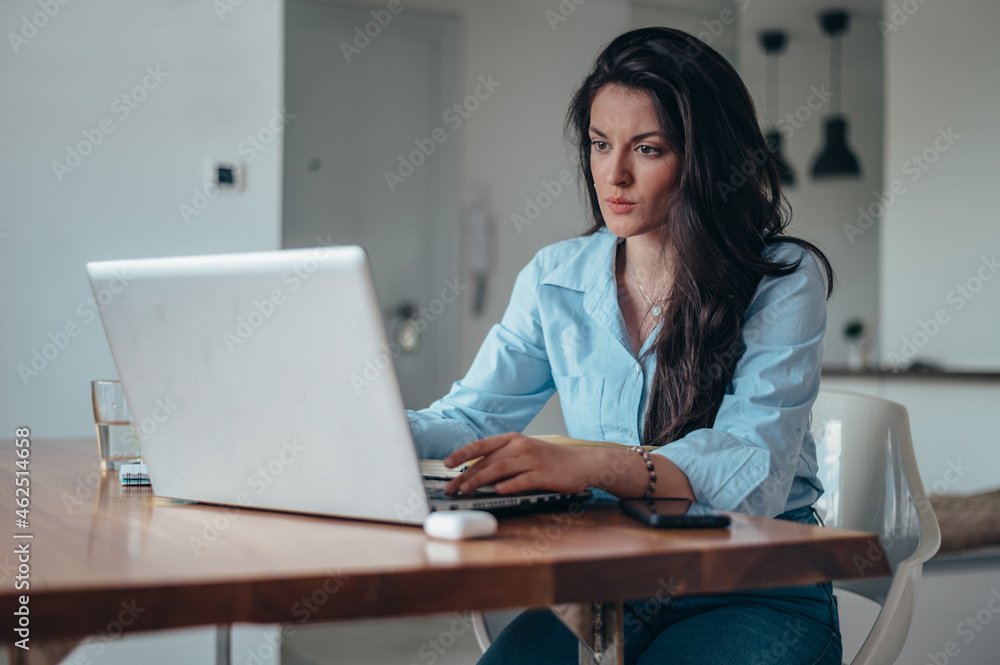 Businesswoman using a laptop while working from home Businesswoman using a laptop while working from home