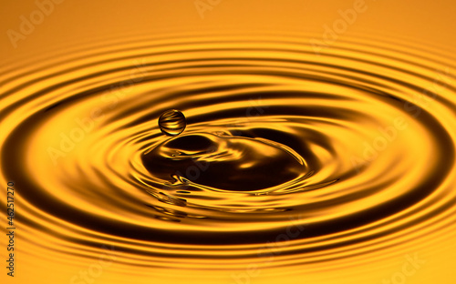 Closeup of a drop of water in the air on a gold background.