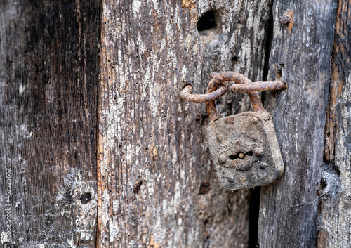 close up of an old wooden door, with an antique padlock, rusty and dirty, with spider webs, antique texture, selective focus and copy space