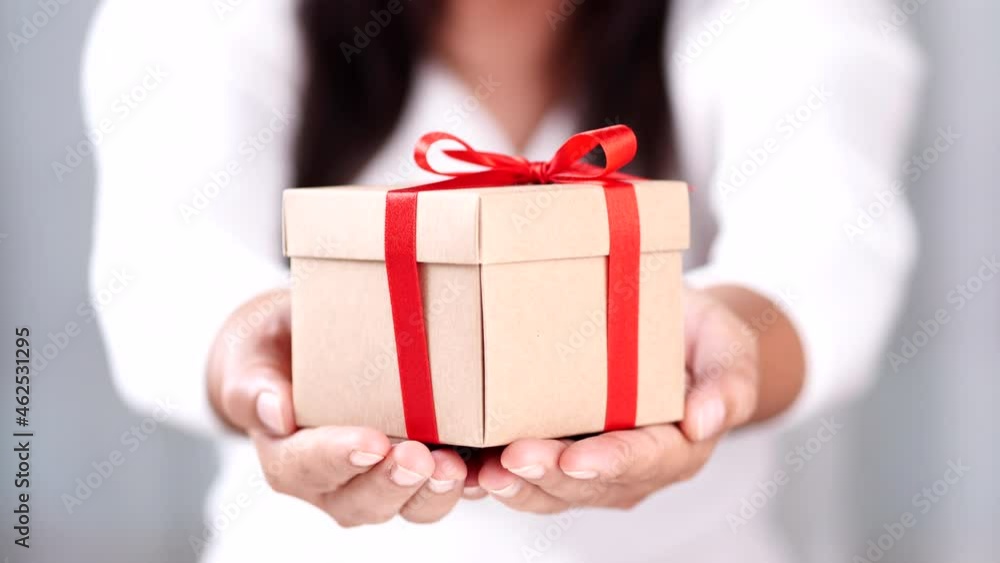 Woman hands holding rustic gift box presents tie with red ribbon bow. Concept Season of giving, Christmas, Happy New Year, Birthday, Valentine, Anniversary, Mother's day. Woman hands holding rustic gift box presents tie with red ribbon bow. Concept Season of giving, Christmas, Happy New Year, Birthday, Valentine, Anniversary, Mother's day.