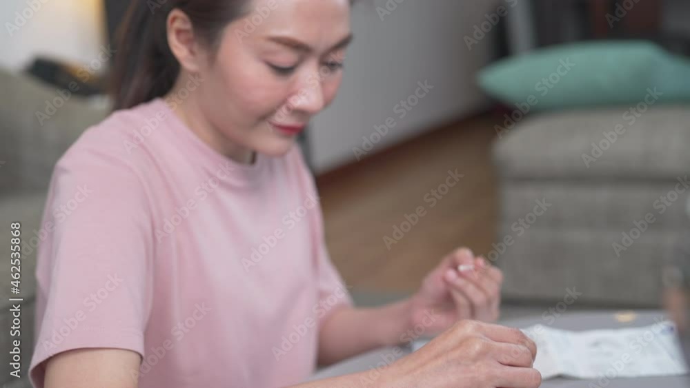 Asian woman using rapid antigen test kit for self test COVID-19 epidemic at home. Adult female unpacking a swab for inserts into her nose. COVID-19 coronavirus pandemic protection concept. Asian woman using rapid antigen test kit for self test COVID-19 epidemic at home. Adult female unpacking a swab for inserts into her nose. COVID-19 coronavirus pandemic protection concept.