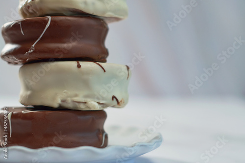 White and brown chocolate alfajores on porcelain plate. photo