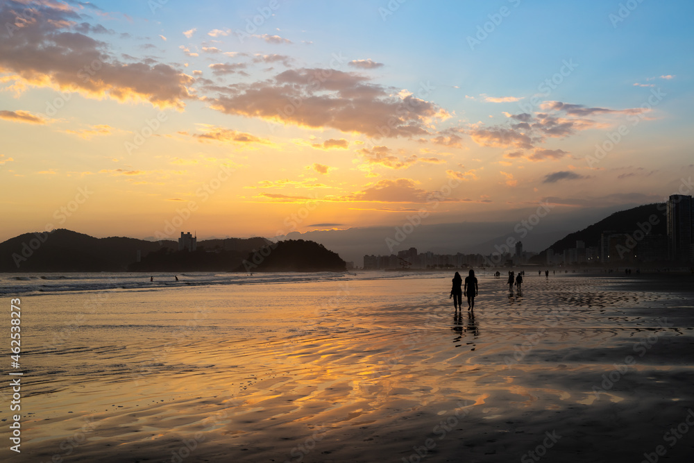 People walking along the seashore during the spring sunset in the city of Santos