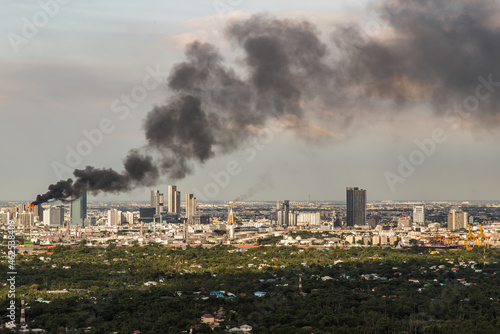 Bangkok, Thailand - 10 Oct, 2021 : Plume of smoke clouds from Burnt industrial or office building on fire at some area in the city. Fire disaster accident, Selective focus.