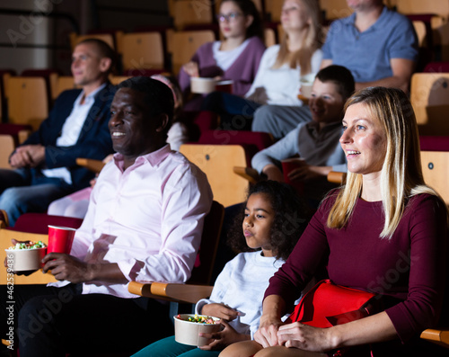 international parents with children sitting at movie in cinema