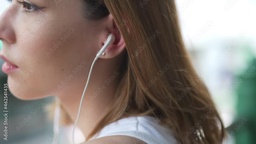 Young beautiful Asian woman walking down city street with listening to the music from earphones on mobile phone application. Pretty girl enjoy urban outdoor lifestyle and city life with happiness Young beautiful Asian woman walking down city street with listening to the music from earphones on mobile phone application. Pretty girl enjoy urban outdoor lifestyle and city life with happiness