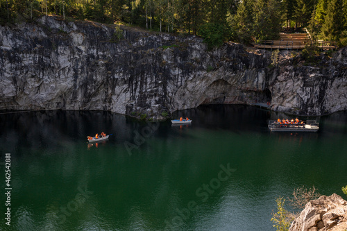 Boats with tourists float on the lake of the Great Marble Canyon in the Republic of Karelia in Russia