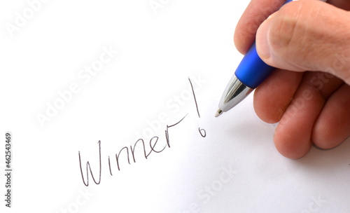 Pen hand-writes Winner on white paper