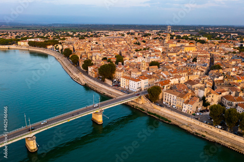 Cityscape of Arles, southern France. Tiled roofs of buildings and Rhone River visible from above.