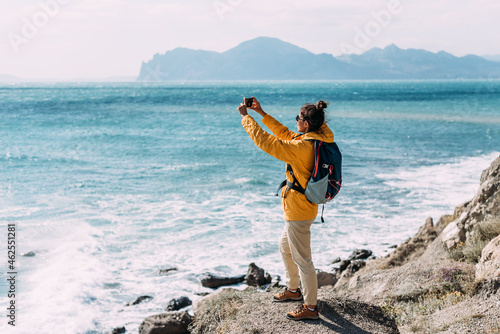 Tableau sur toile A traveler with a phone on the background of the sea, rear view