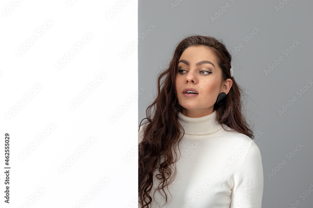 beautiful sensual woman with long curly hair shows a blank banner, isolated on gray, copy space beautiful sensual woman with long curly hair shows a blank banner, isolated on gray, copy space