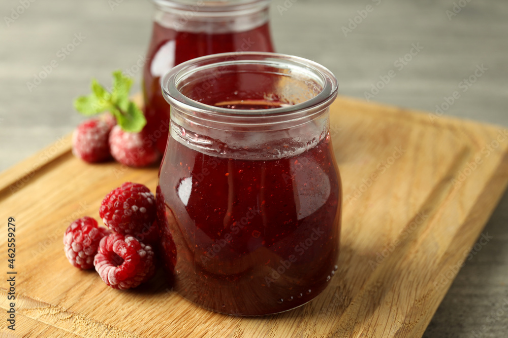 Glass jars of raspberry jam with ingredients on wooden board Glass jars of raspberry jam with ingredients on wooden board