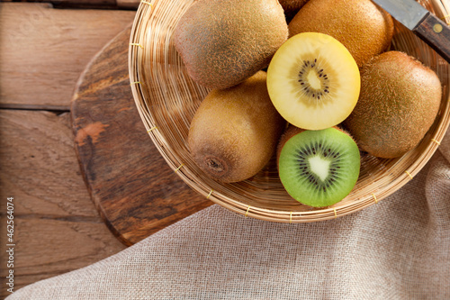 Top view ripe golden kiwi fruit and green kiwi fruit in wood basket on wooden table background. Healthy fruits concept.