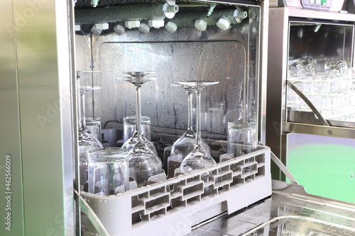 Open dishwasher with clean glass, cups, plates and dishes, selective focus