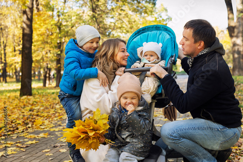Young family with small children in the park. Happy smiling parents. Love and tenderness. Golden autumn season.