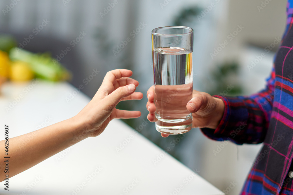 Frame image of a little girl hand holding a glass of water in the kitchen with the young mother. Frame image of a little girl hand holding a glass of water in the kitchen with the young mother.