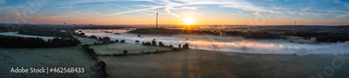Fotografie Sunrise and the first rays of sunshine over the fog-covered Ruhr meadows in Duis
