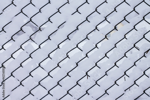 Winter creative background image. Snow, lying on mesh cells of chain-link