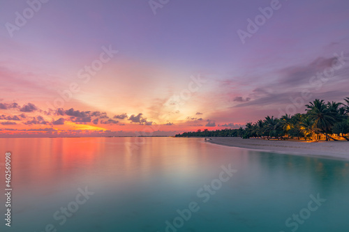 Beautiful bright sunset on a tropical paradise beach. Tranquil summer vacation or holiday landscape. Tropical sunset beach view with palm over calm sea water, Exotic nature view, inspirational scenic
