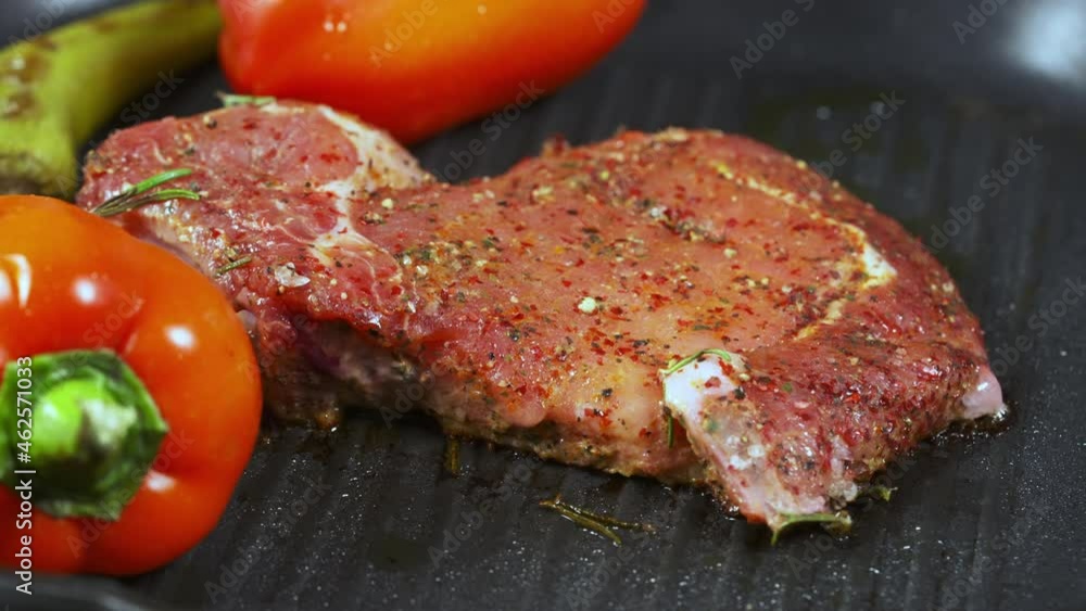 Portion of raw meat on a griddle with fresh vegetables Portion of raw meat on a griddle with fresh vegetables
