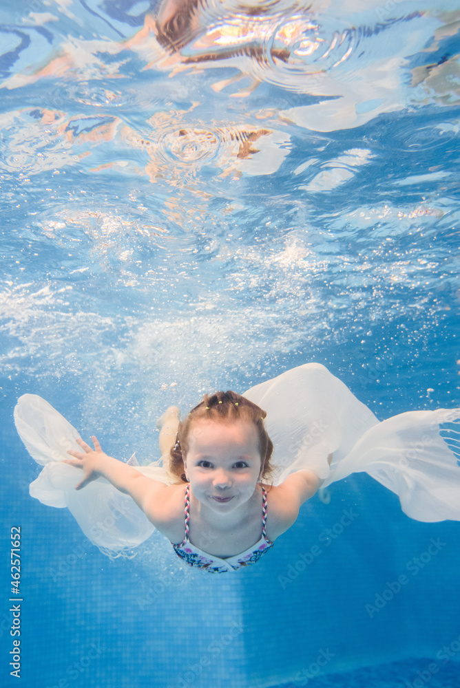 Little kid girl swimming underwater in the paddling pool. Diving ...