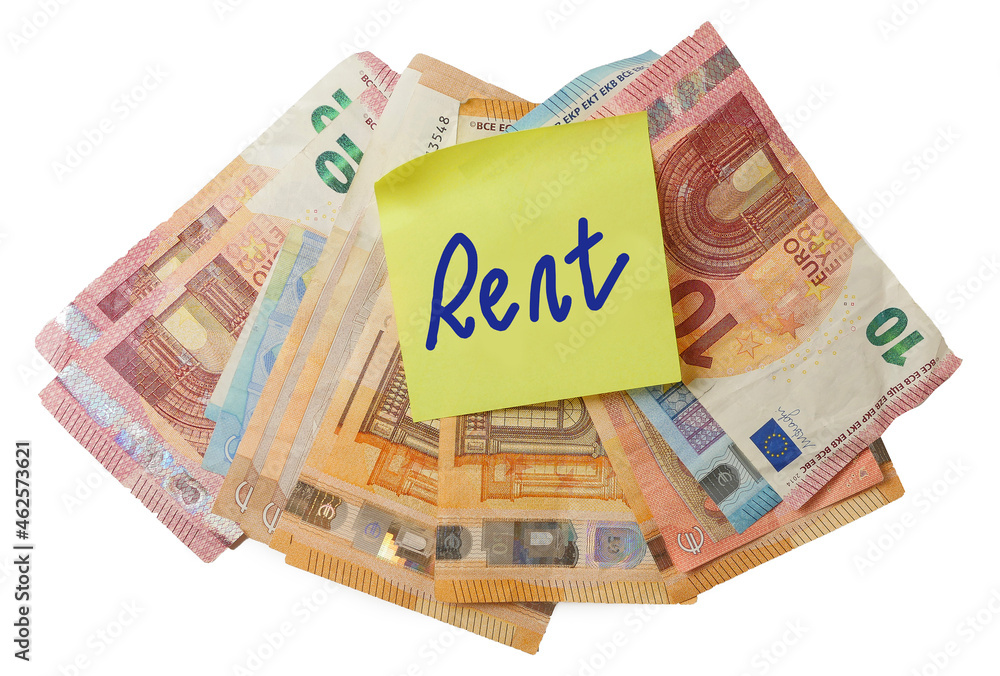 Yellow sticker with hand written sign rent on pile of Euro bank notes on white isolated background. Paying household bills concept Yellow sticker with hand written sign rent on pile of Euro bank notes on white isolated background. Paying household bills concept