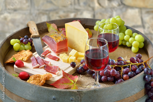 Südtiroler Marende mit klassischen Spezialitäten auf einem Weinfaß dazu regionaler Rotwein - South Tyrolean snack with bacon, mountain cheese,  crunchy rye bread and a local red wine