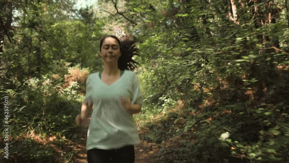 Cross-country running. A young woman in sports clothes runs out from the left side, through the morning summer forest. In real time. The concept of a healthy lifestyle. Cross-country running. A young woman in sports clothes runs out from the left side, through the morning summer forest. In real time. The concept of a healthy lifestyle.
