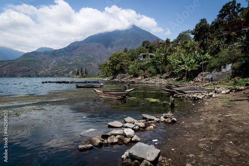 Bay at lake Atitlan with small fishing boats with view on forest and volcanic mountain landscape, Santiago Atitlan, Guatemala photo
