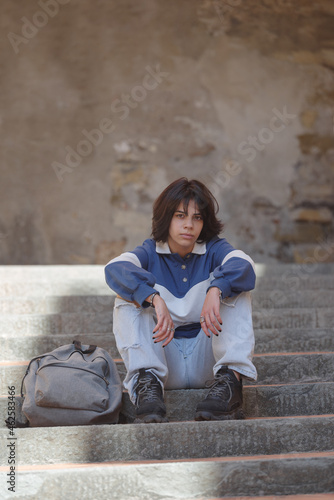 Teenage student with backpack sitting on steps in the street of the Italian old town