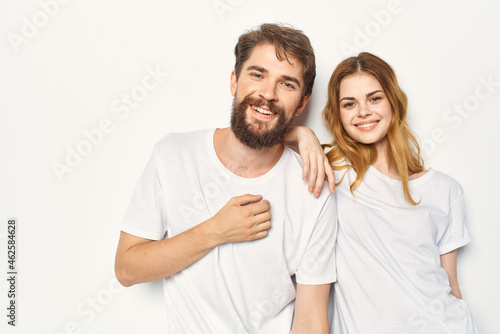 Cheerful man and woman in white t-shirts embrace friendship together