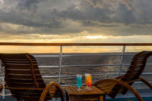 Sun loungers to enjoy the ocean views  with a cocktail table next to it on the ship s deck.
