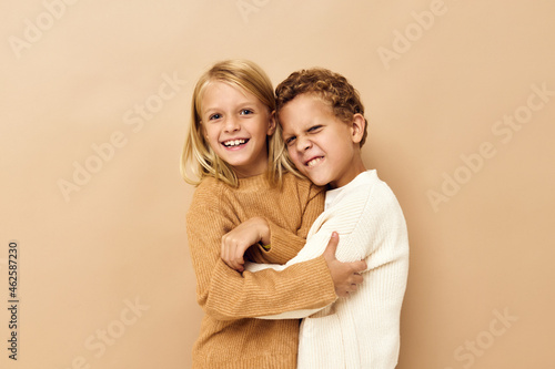 boy and girl smiling and posing in casual clothes beige background