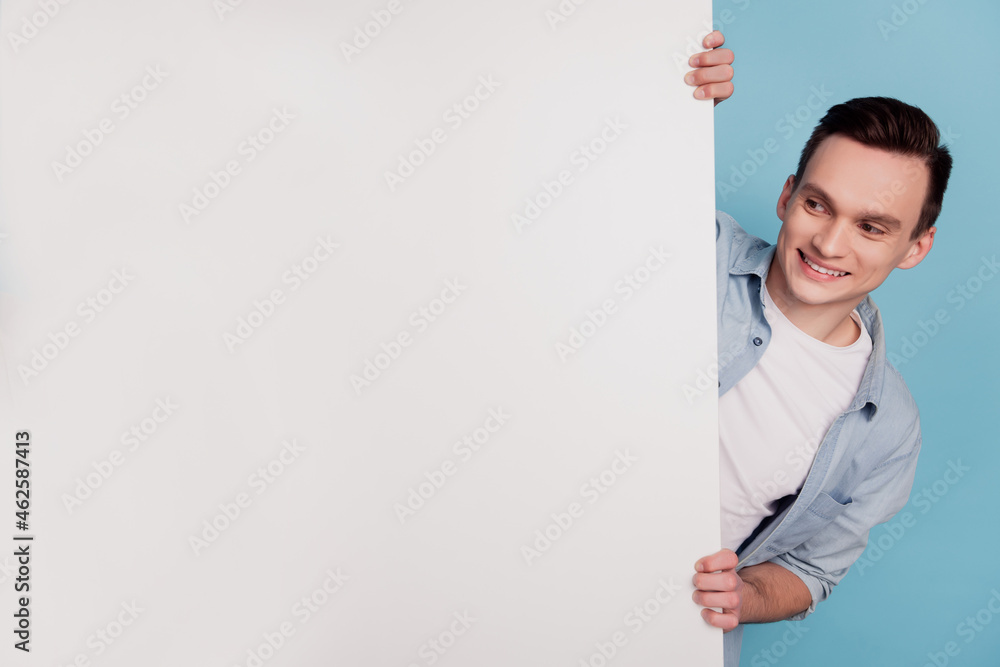 Photo portrait of cheerful student keeping hands on white placard blank space isolated on vivid blue color background Photo portrait of cheerful student keeping hands on white placard blank space isolated on vivid blue color background