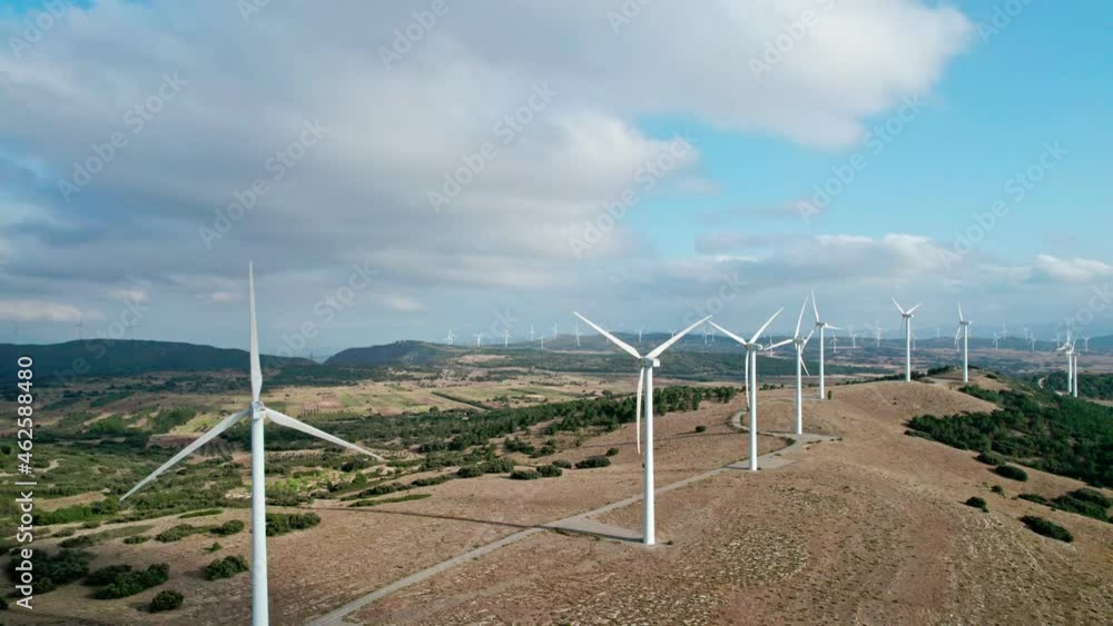 Aerial view of a windmill farm for energy production against beautiful cloudy sky in the mountains. Wind turbines generating clean renewable energy for sustainable development Aerial view of a windmill farm for energy production against beautiful cloudy sky in the mountains. Wind turbines generating clean renewable energy for sustainable development