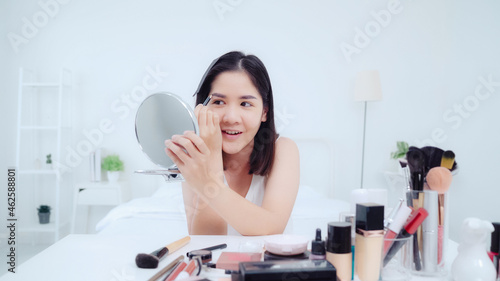 Beauty blogger present beauty cosmetics sitting in front camera for recording video. Happy beautiful young Asian woman use cosmetics review make up tutorial broadcast live video to social network.