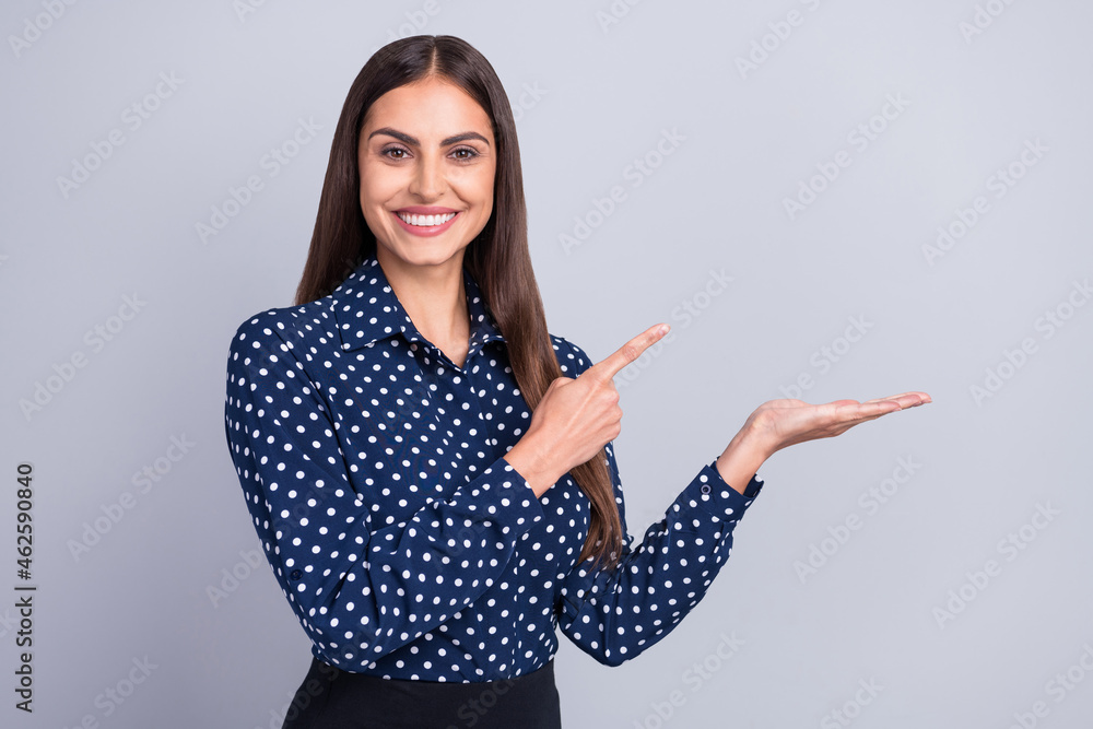 Photo of cheerful lady hold palm indicate finger empty space wear dotted blouse isolated grey color background Photo of cheerful lady hold palm indicate finger empty space wear dotted blouse isolated grey color background