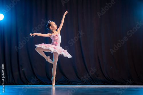 little girl ballerina is dancing on stage in white tutu on pointe shoes classic variation Fototapeta