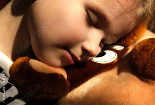 Closeup  of a little girl embracing her teddy bear, lonely in the dark. in dark settings photo