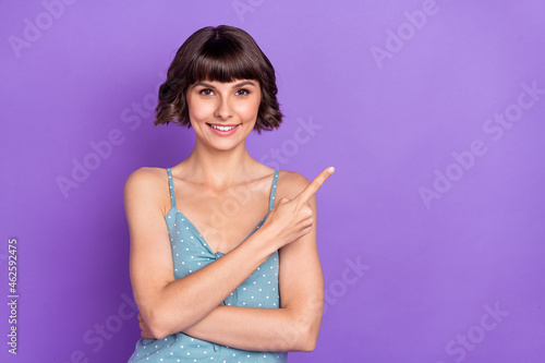 Portrait of attractive cheerful girl demonstrating copy space ad isolated over bright violet purple color background