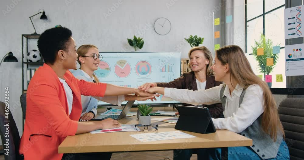 Happy successful female team celebrate good teamwork result achieved corporate goals at briefing table in office Happy successful female team celebrate good teamwork result achieved corporate goals at briefing table in office
