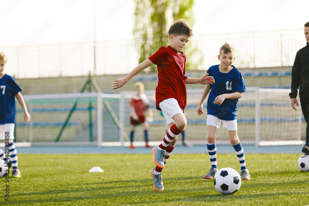 Youth Junior Athletes in Red and Blue Soccer Shirts. Two Boys Compete for the Ball. Sports Education. Kids Football Players Kicking Ball on Soccer Field. Sports Soccer Horizontal Background