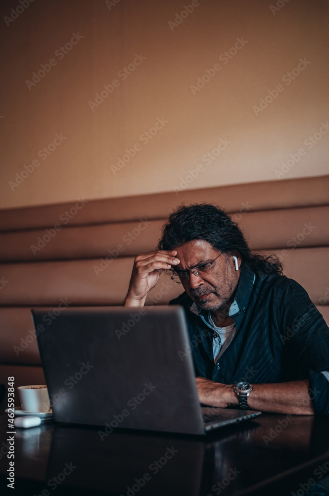 Senior hispanic cuban men using a laptop while having a headache from work stress Senior hispanic cuban men using a laptop while having a headache from work stress