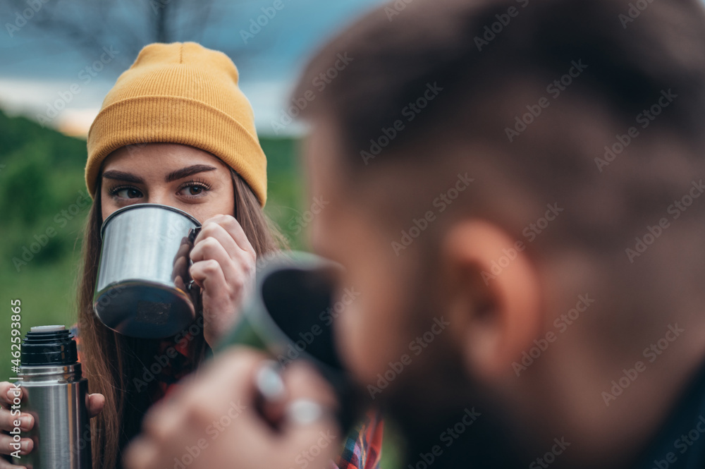 Naklejka premium Couple of campers drinking coffee from a metal cups