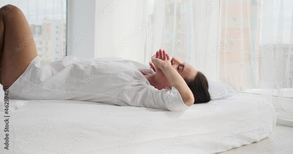 Happy young woman lying on bed in bedroom at home Happy young woman lying on bed in bedroom at home