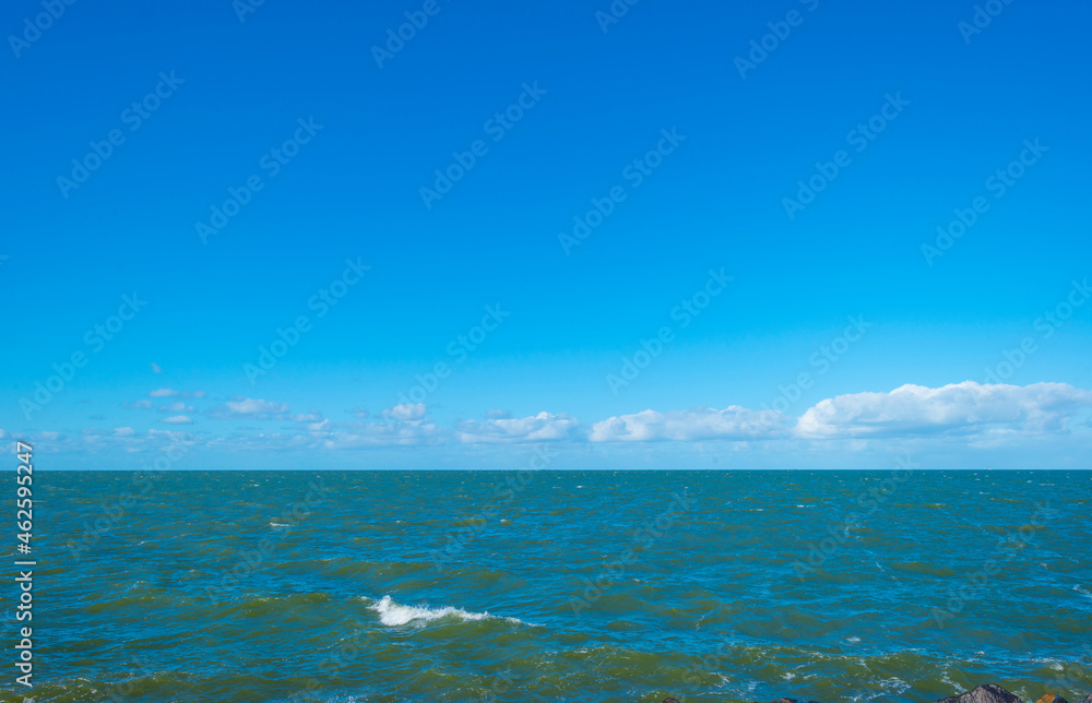 Waves in a lake along a dam under a bright blue sky in bright sunlight in autumn, Almere, Flevoland, The Netherlands, October 12, 2021
