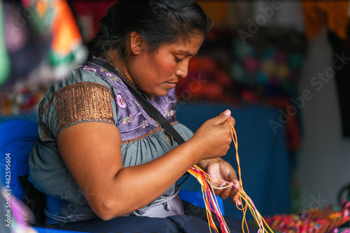young Mexican woman embroidering typical regional blouses and shirts