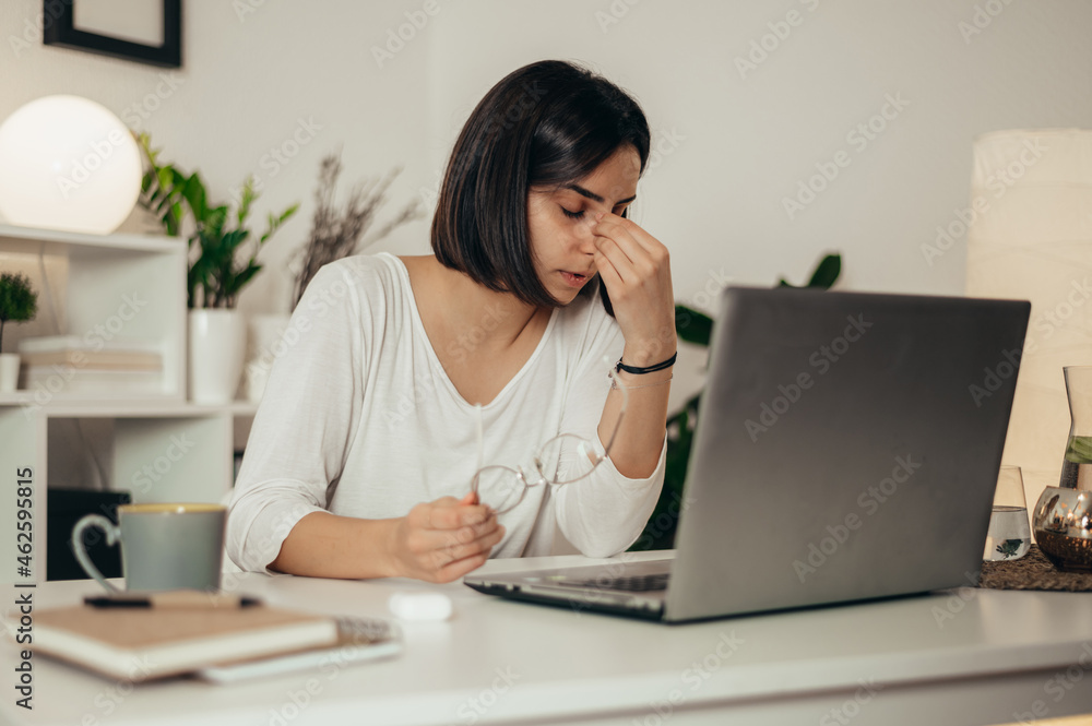 Woman feeling tired and stressed while using a laptop and working from home Woman feeling tired and stressed while using a laptop and working from home